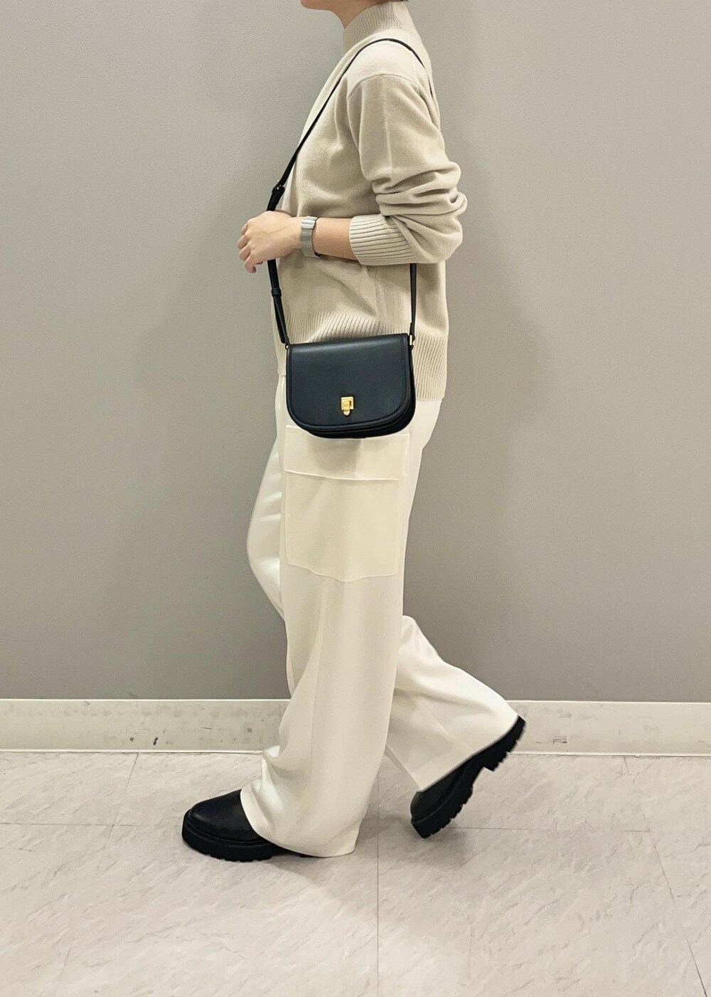 ブラック系のショルダーバッグ、ブラック系のブーツ、ベージュ系のニット/セーターを着用したレディースの秋コーディネートの4枚目の写真