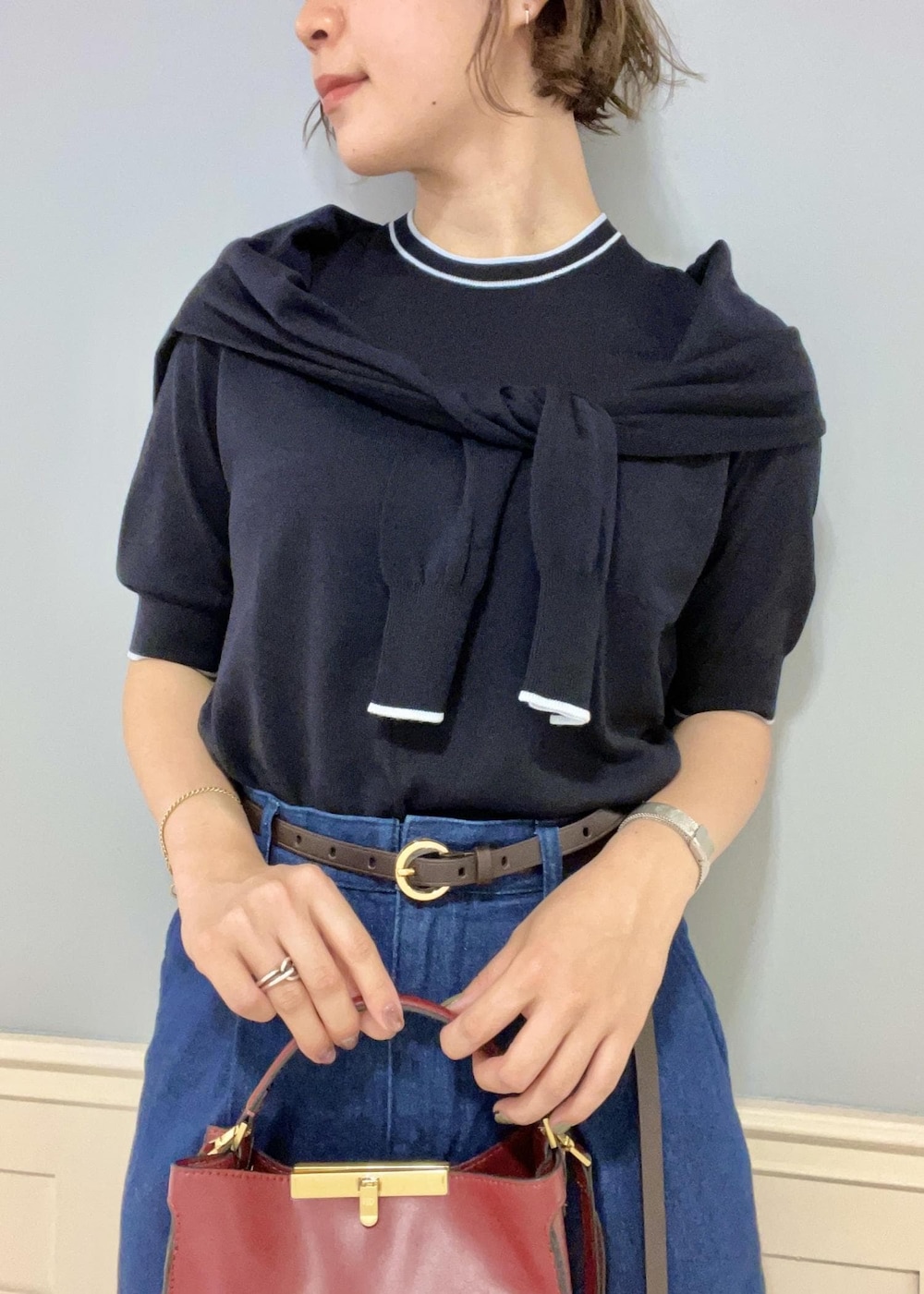 レッド系のショルダーバッグ、ブルー系のカーディガン/ボレロ、ブラック系のパンプスを着用したレディースの夏コーディネートの6枚目の写真