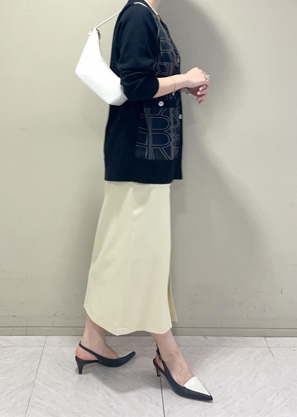 ブラック系のパンプス、ベージュ系のスカート、ブラック系のカーディガン/ボレロを着用したレディースの冬コーディネートの5枚目の写真