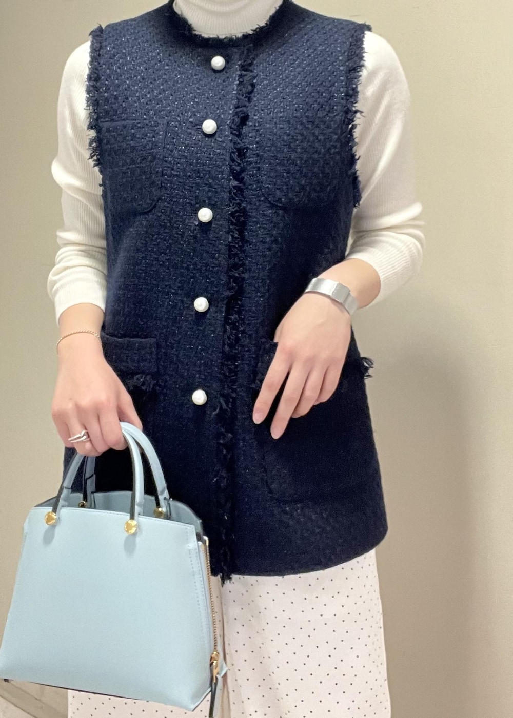 ブラック系のパンプス、ブルー系のハンドバッグ、ホワイト系のニット/セーターを着用したレディースの冬コーディネートの7枚目の写真