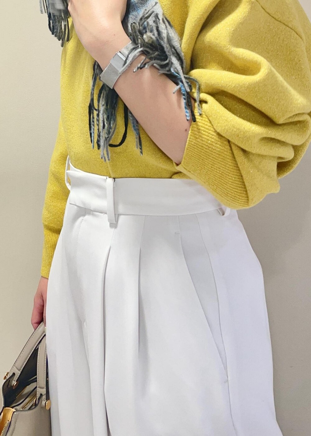 ベージュ系のハンドバッグ、ブラック系のブーツ、イエロー系のニット/セーターを着用したレディースの冬コーディネートの7枚目の写真