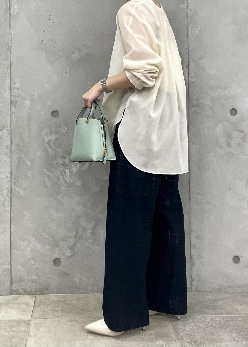 グリーン系のハンドバッグ、ベージュ系のパンプス、ブラック系のその他パンツを着用したレディースの春コーディネートの5枚目の写真