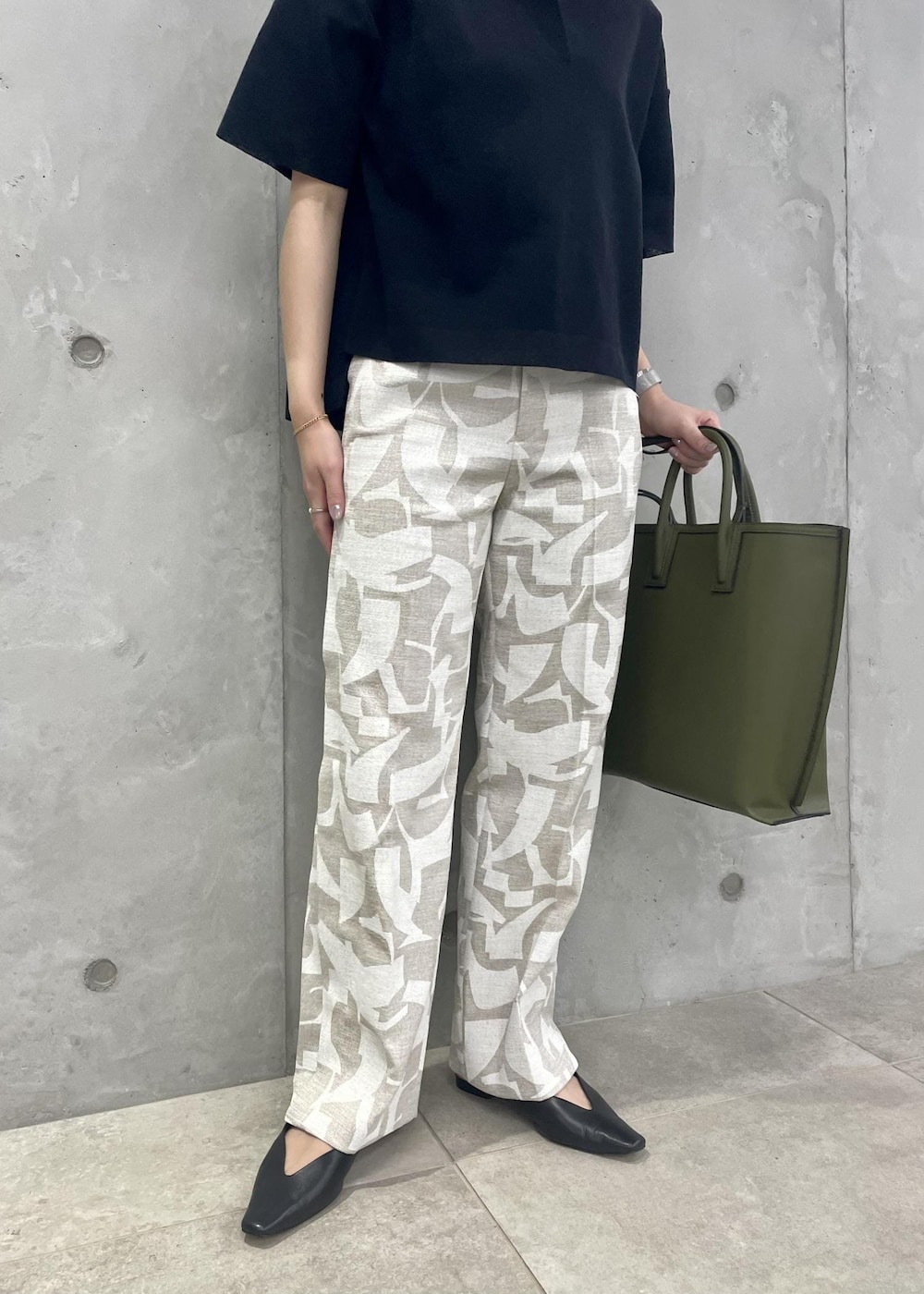 グリーン系のトートバッグ、ブラック系のパンプス、ブルー系のニット/セーターを着用したレディースの春コーディネートの7枚目の写真