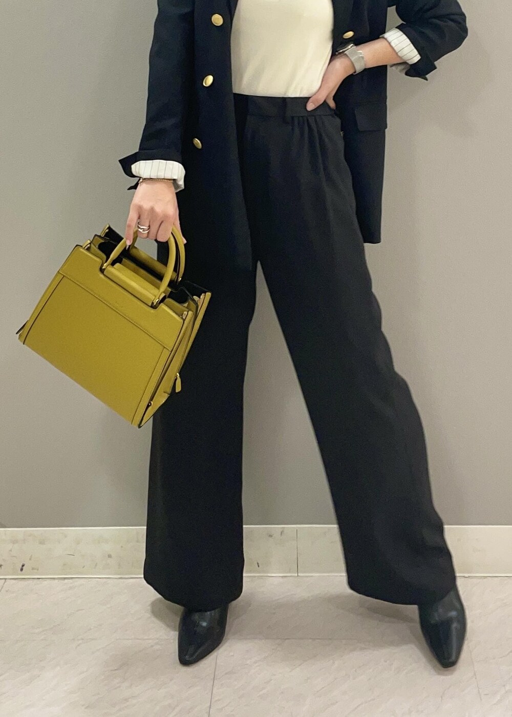 ブルー系のテーラードジャケット、イエロー系のハンドバッグ、ブラック系のブーツを着用したレディースの秋コーディネートの6枚目の写真
