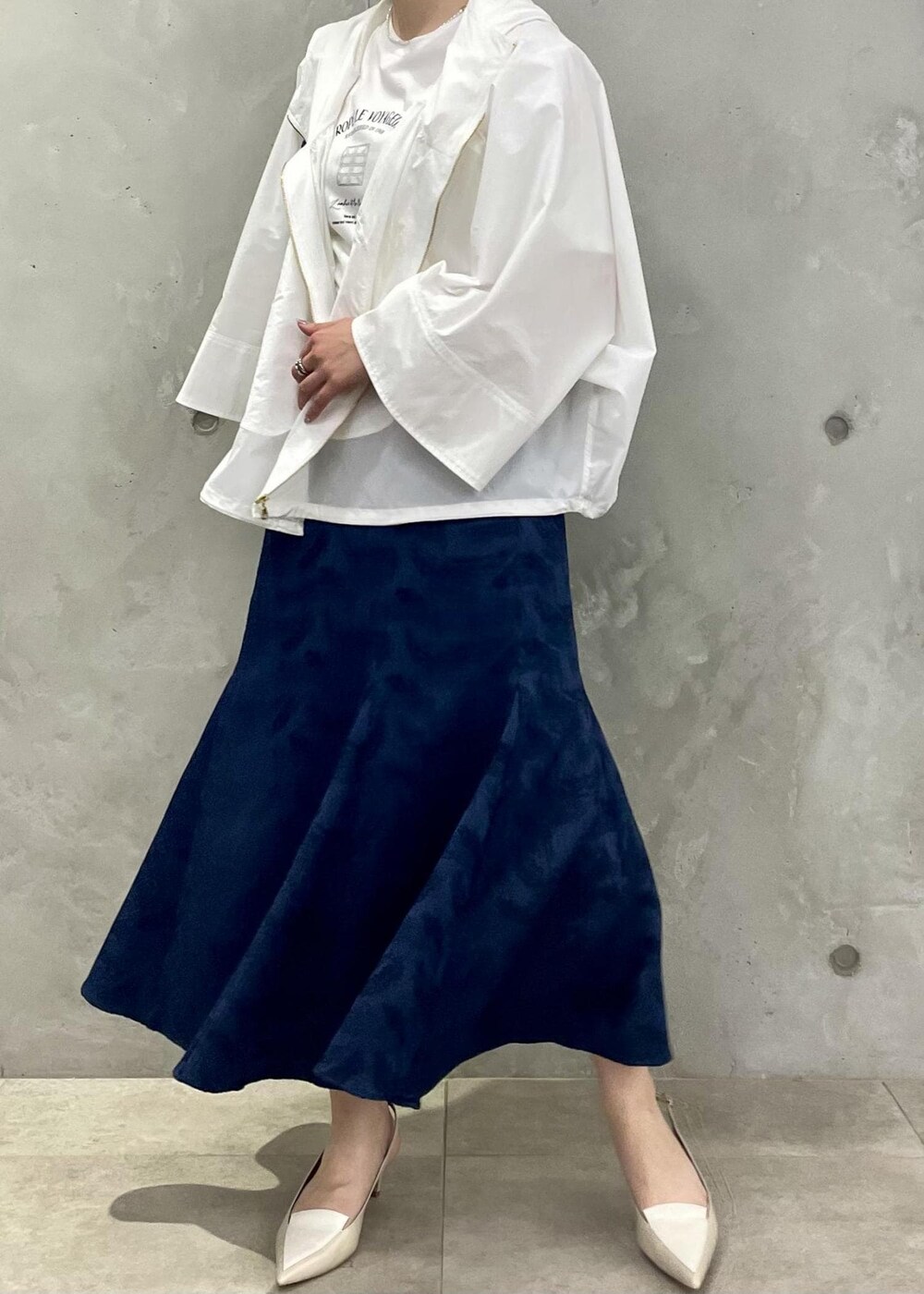 ベージュ系のパンプス、ブルー系のスカート、ホワイト系のマウンテンパーカーを着用したレディースの春コーディネートの5枚目の写真