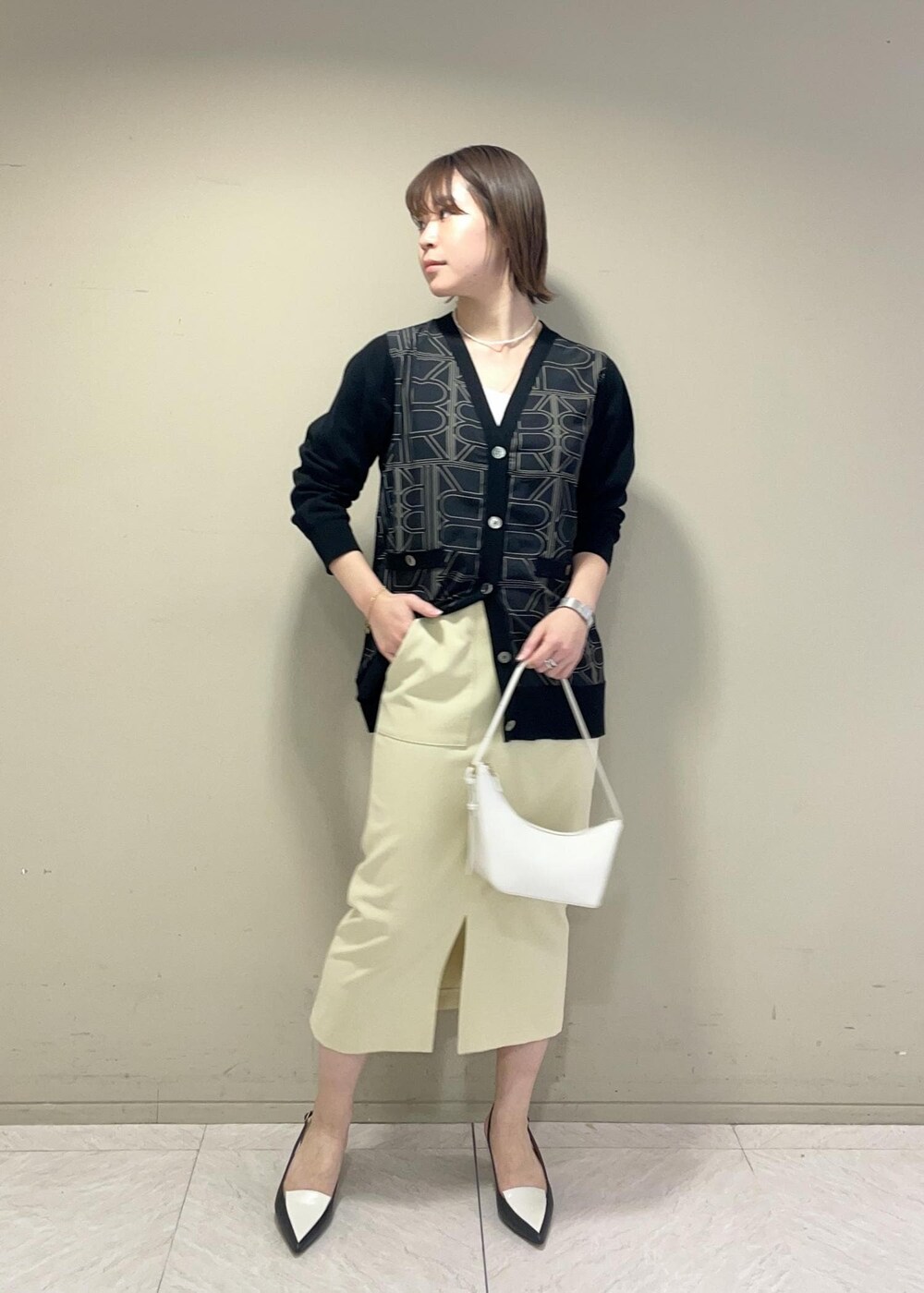 ブラック系のパンプス、ベージュ系のスカート、ブラック系のカーディガン/ボレロを着用したレディースの冬コーディネートの2枚目の写真