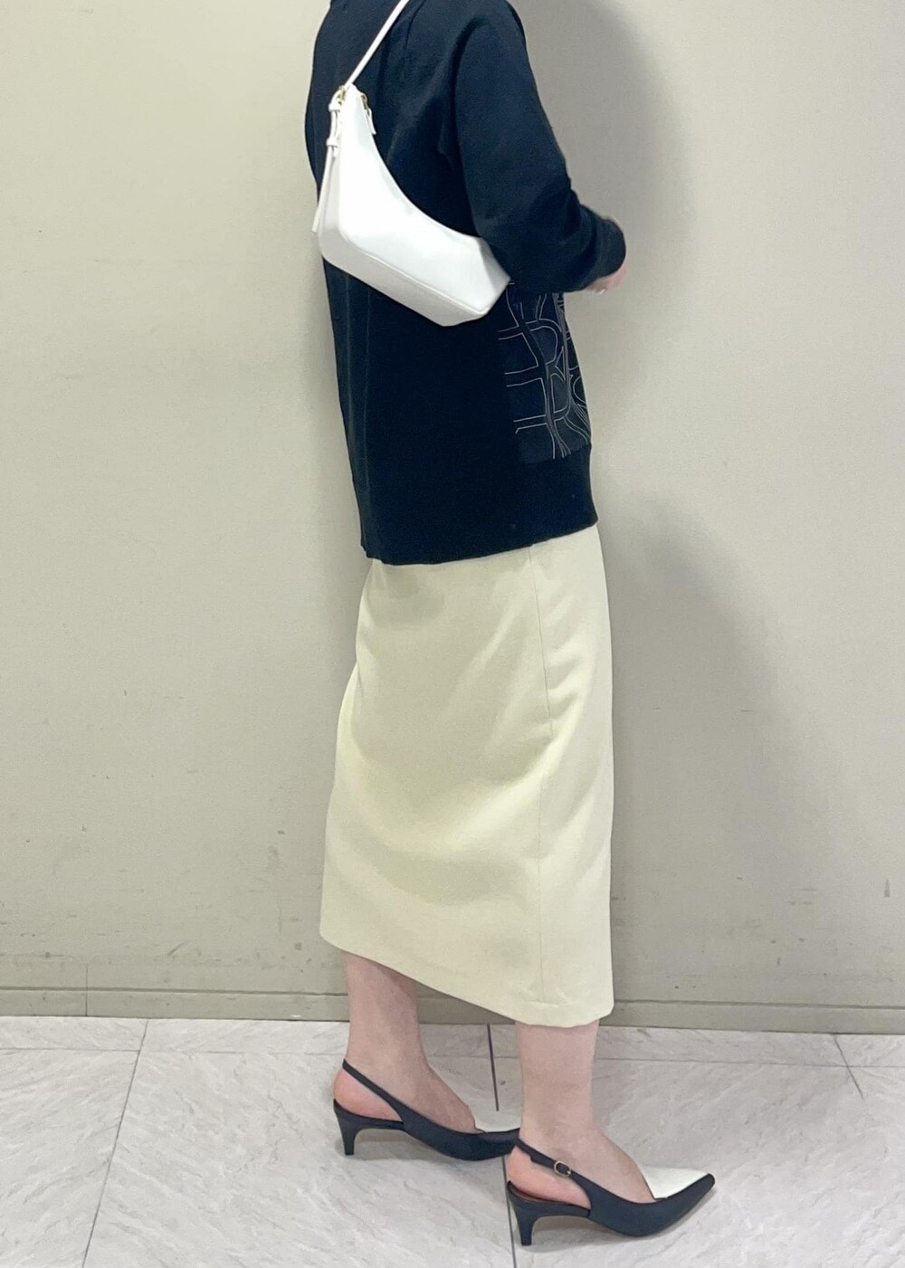 ブラック系のパンプス、ベージュ系のスカート、ブラック系のカーディガン/ボレロを着用したレディースの冬コーディネートの6枚目の写真