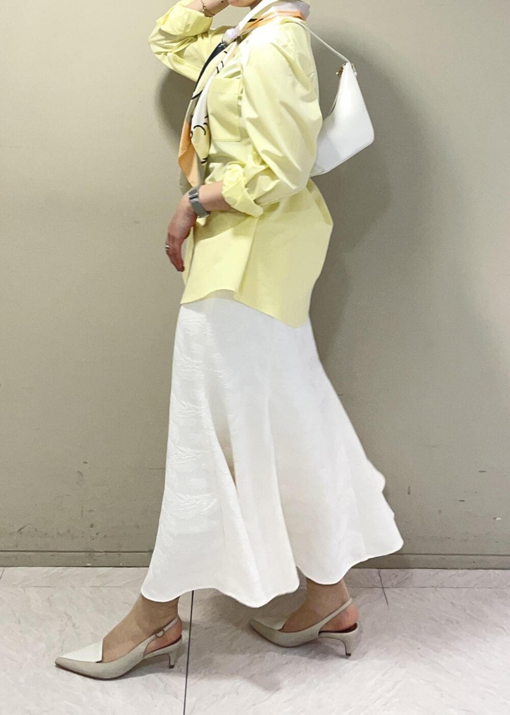 ベージュ系のハンドバッグ、イエロー系のシャツ/ブラウス、ベージュ系のパンプスを着用したレディースの春コーディネートの5枚目の写真