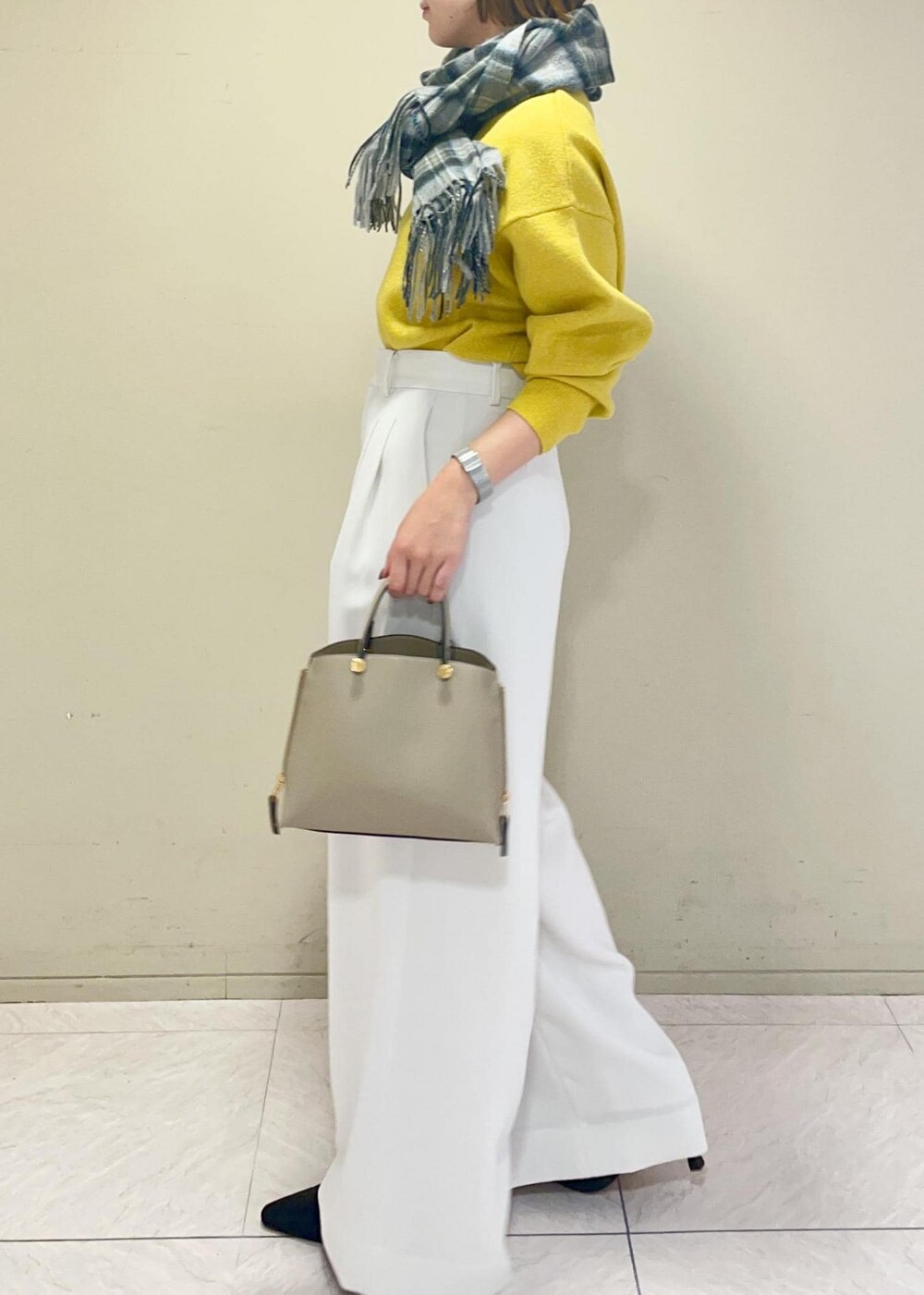 ベージュ系のハンドバッグ、ブラック系のブーツ、イエロー系のニット/セーターを着用したレディースの冬コーディネートの3枚目の写真