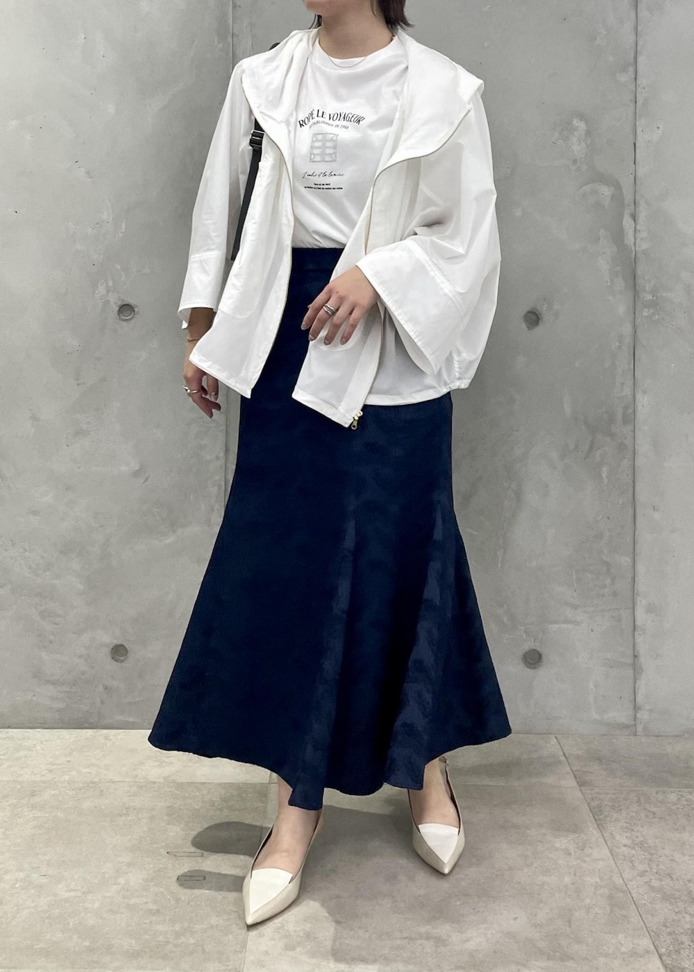 ベージュ系のパンプス、ブルー系のスカート、ホワイト系のマウンテンパーカーを着用したレディースの春コーディネートの2枚目の写真