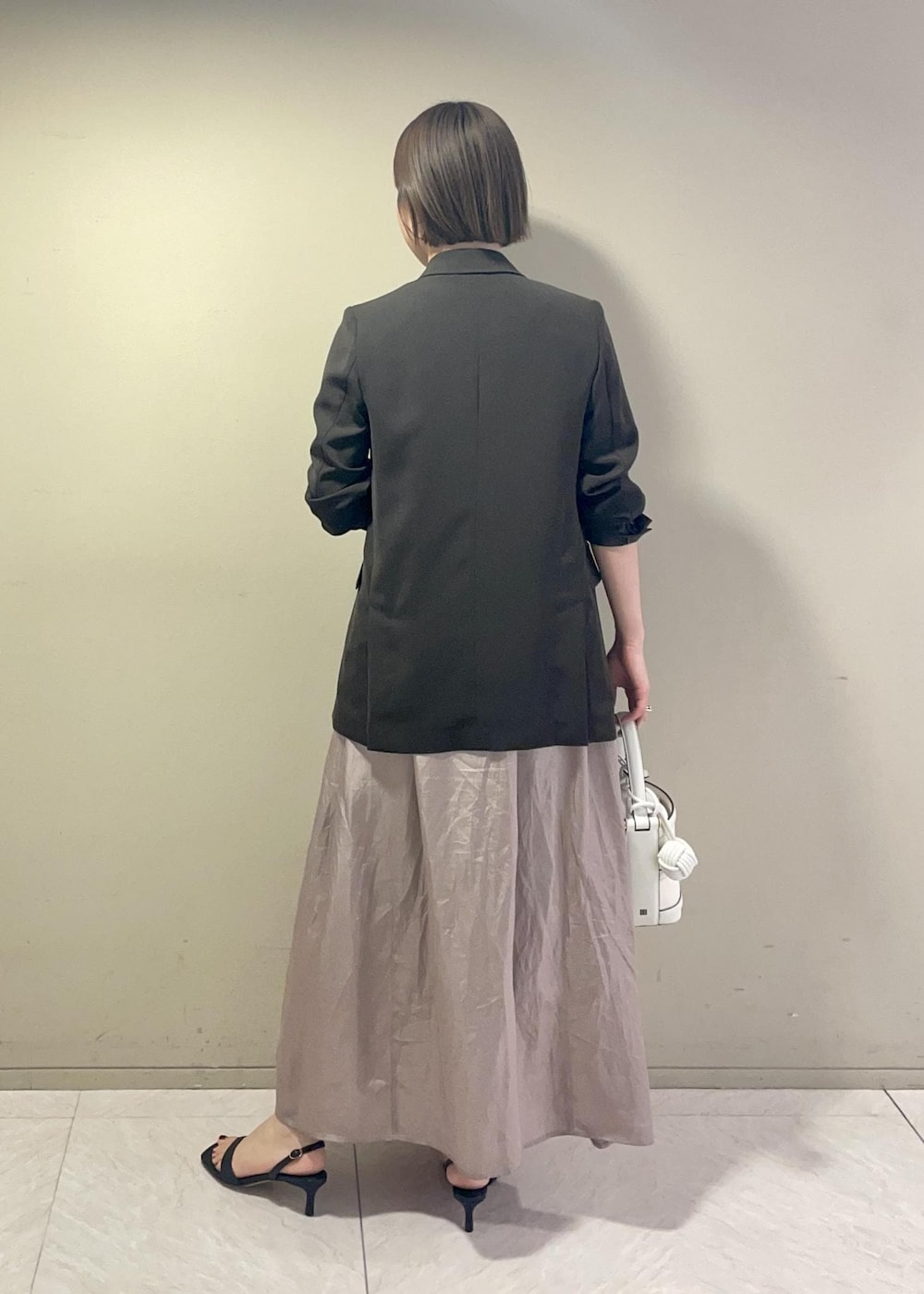 ホワイト系のハンドバッグ、ブラック系のサンダル、ブラウン系のテーラードジャケットを着用したレディースの春コーディネートの5枚目の写真