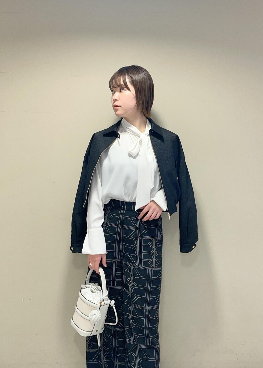 ホワイト系のハンドバッグ、ブラック系のその他パンツ、ブラック系のブルゾンを着用したレディースの冬コーディネートの2枚目の写真