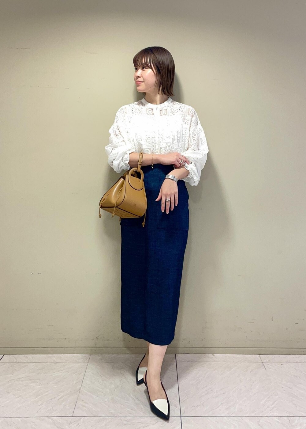 イエロー系のショルダーバッグ、ブルー系のスカート、ブラック系のパンプスを着用したレディースの冬コーディネートの2枚目の写真