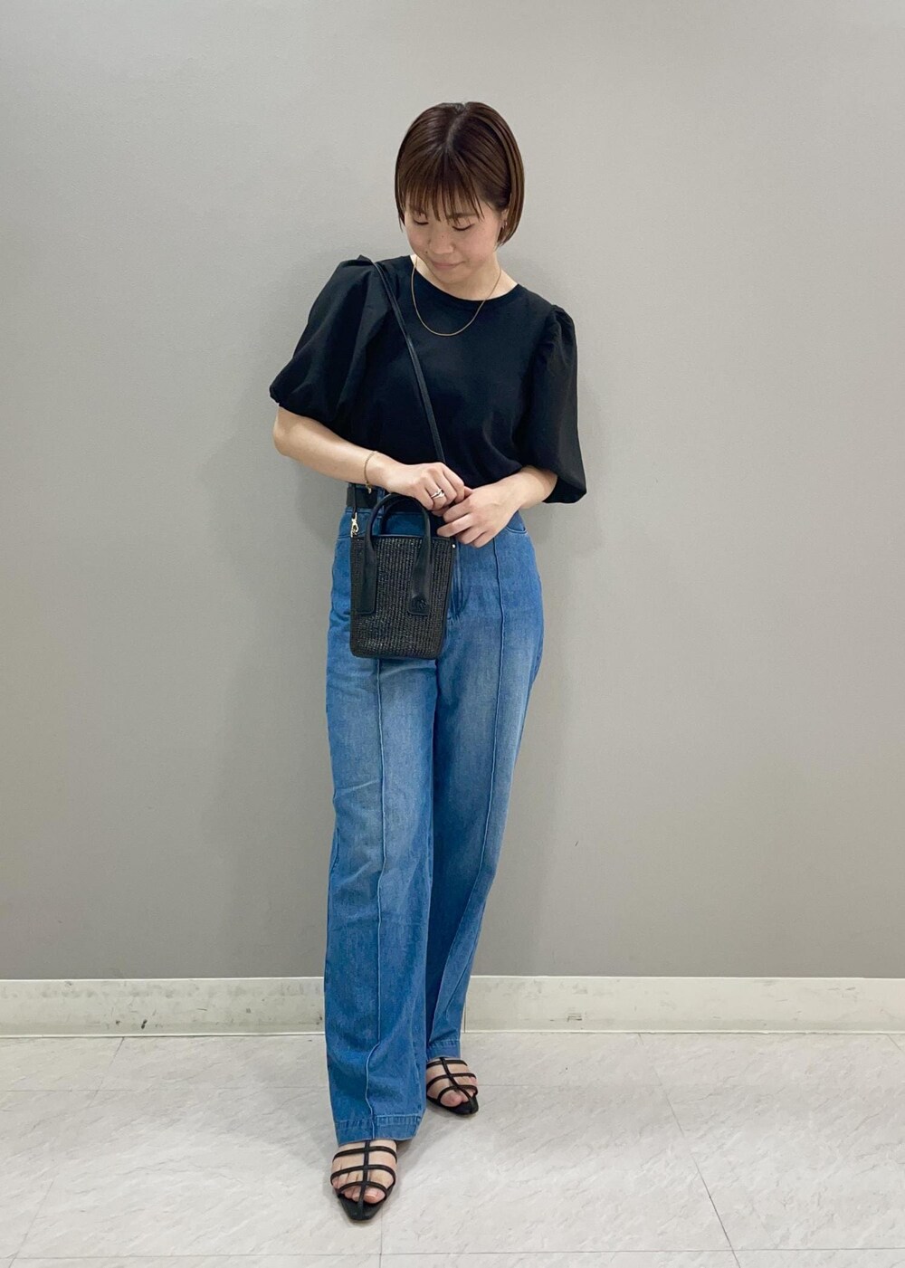 ブラック系のサンダル、ブラック系のハンドバッグ、ブラック系のTシャツ/カットソーを着用したレディースの夏コーディネートの2枚目の写真