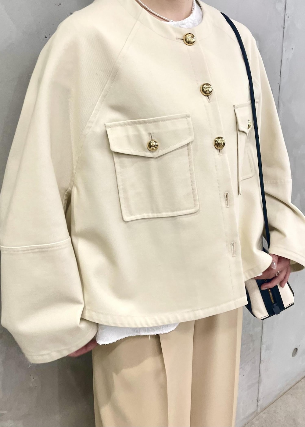 ブラック系のパンプス、ホワイト系のブルゾン、ブラック系のショルダーバッグを着用したレディースの春コーディネートの6枚目の写真