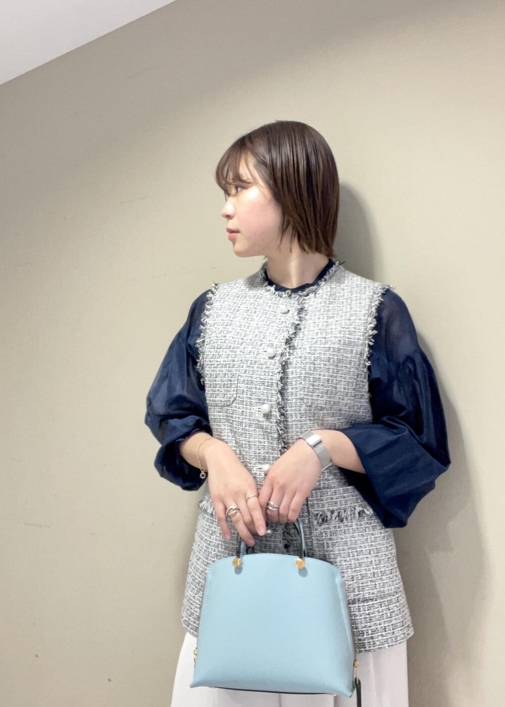 ブラック系のパンプス、ブルー系のハンドバッグ、ブラック系のベストを着用したレディースの冬コーディネートの5枚目の写真