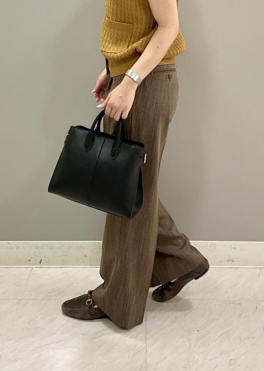 イエロー系のベスト、ブラック系のトートバッグ、ブラウン系のその他パンツを着用したレディースの夏コーディネートの5枚目の写真