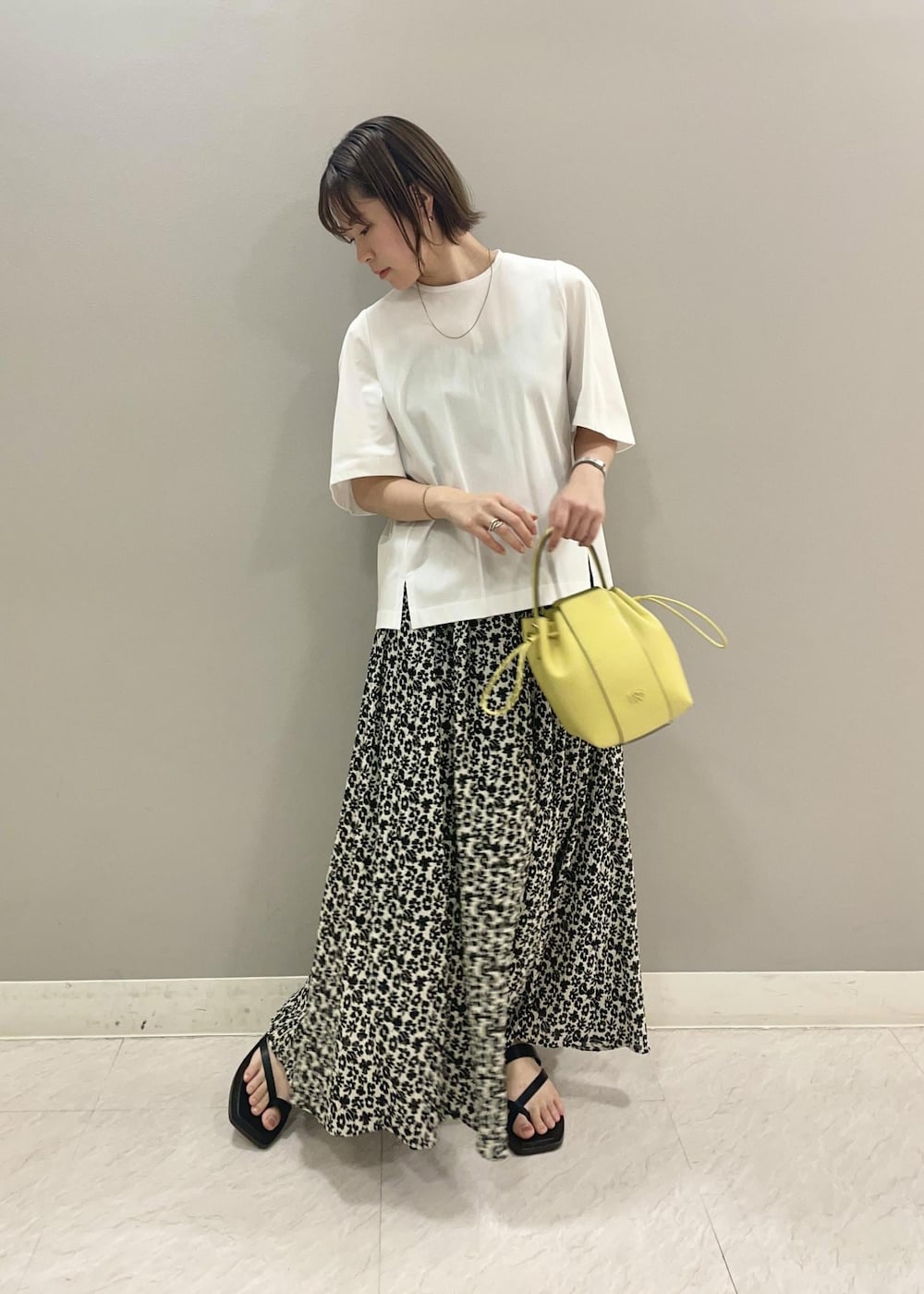 ベージュ系のハンドバッグ、ホワイト系のTシャツ/カットソー、ブラック系のスカートを着用したレディースの夏コーディネートの2枚目の写真