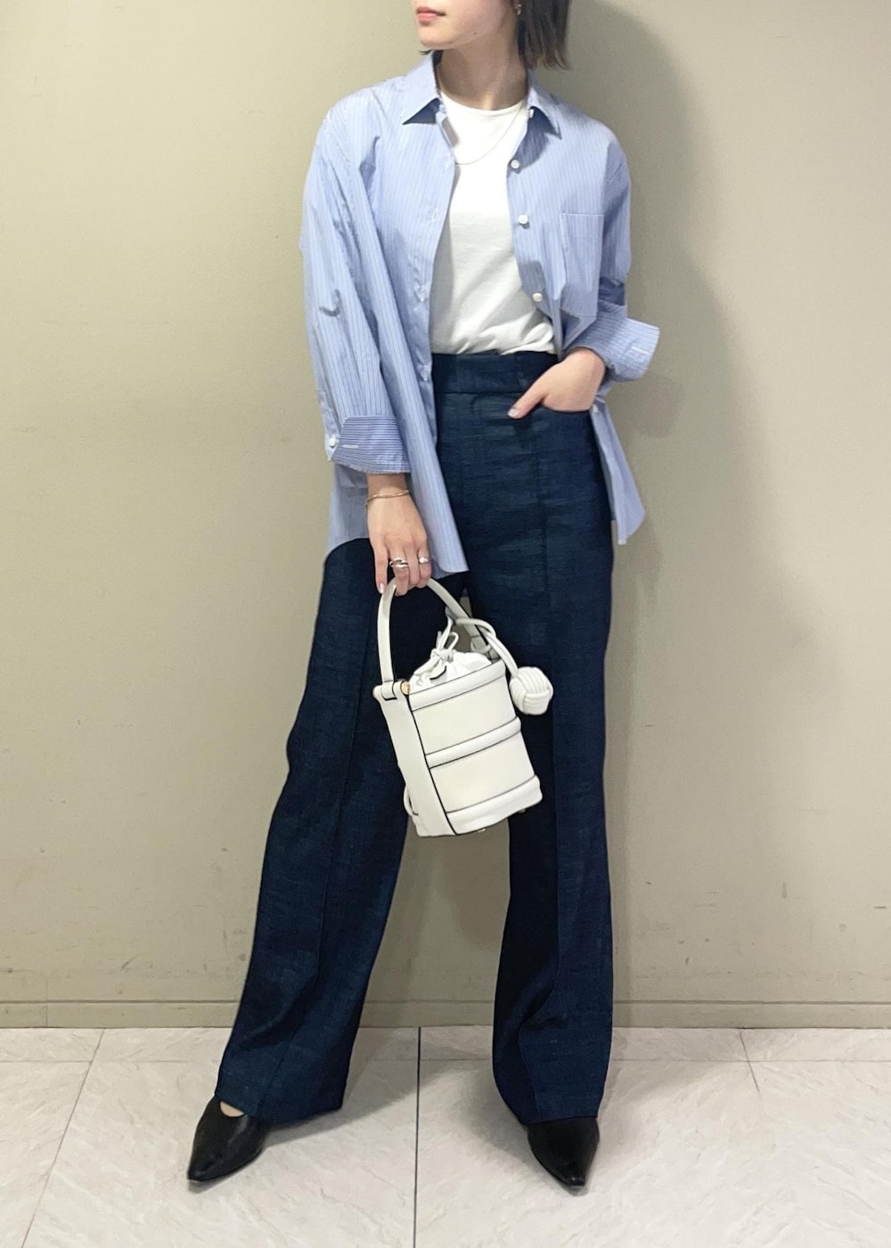 ホワイト系のハンドバッグ、ブルー系のデニムパンツ、ブルー系のシャツ/ブラウスを着用したレディースの春コーディネートの4枚目の写真