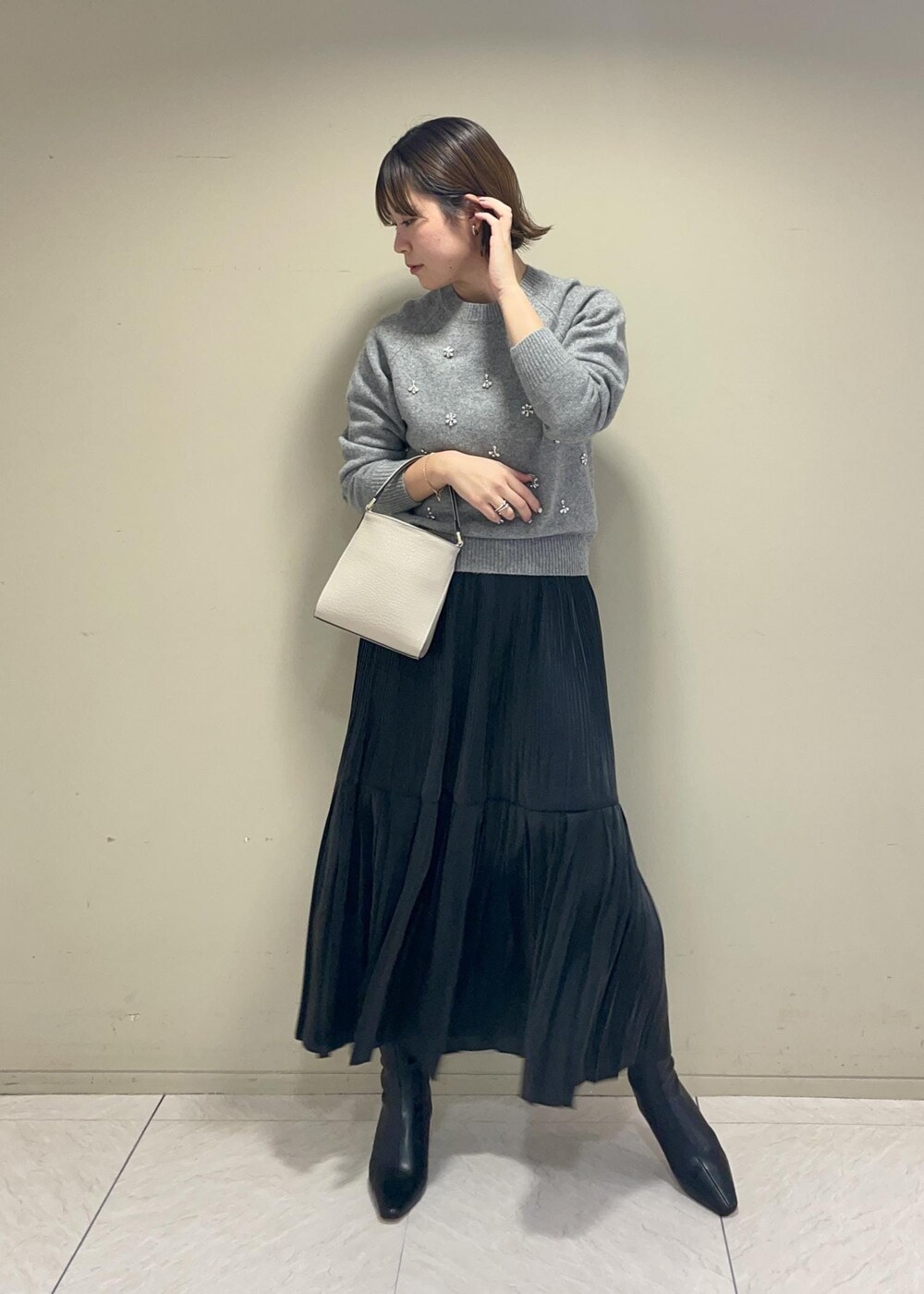 ブラック系のブーツ、ブラック系のスカート、ベージュ系のショルダーバッグを着用したレディースの秋コーディネートの2枚目の写真