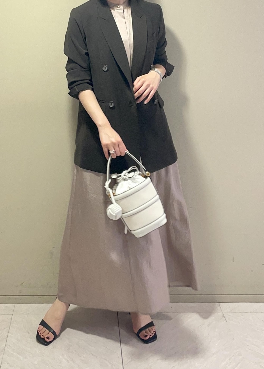 ホワイト系のハンドバッグ、ブラック系のサンダル、ブラウン系のテーラードジャケットを着用したレディースの春コーディネートの3枚目の写真