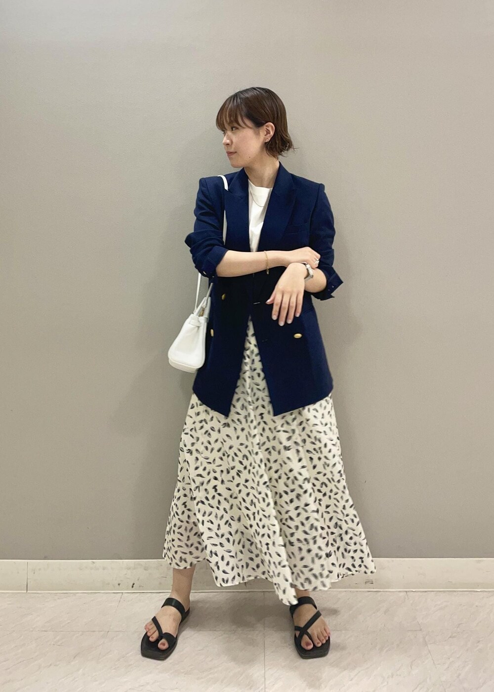 ホワイト系のハンドバッグ、ホワイト系のTシャツ/カットソー、ブルー系のテーラードジャケットを着用したレディースの夏コーディネートの2枚目の写真