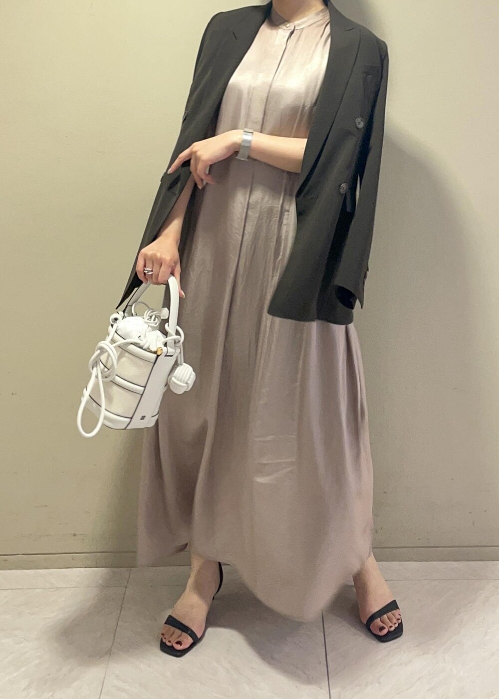 ホワイト系のハンドバッグ、ブラック系のサンダル、ブラウン系のテーラードジャケットを着用したレディースの春コーディネートの6枚目の写真