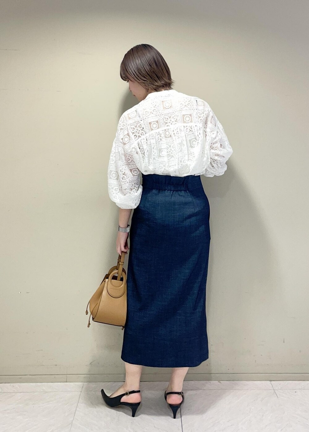 イエロー系のショルダーバッグ、ブルー系のスカート、ブラック系のパンプスを着用したレディースの冬コーディネートの4枚目の写真