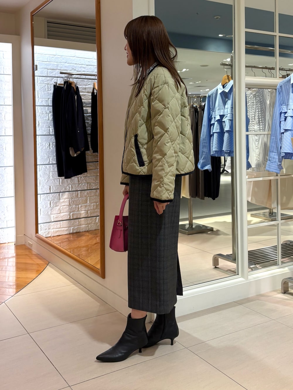 ベージュ系のショルダーバッグ、ベージュ系のダウンジャケット/コート、ブルー系のニット/セーターを着用したレディースの秋コーディネートの4枚目の写真