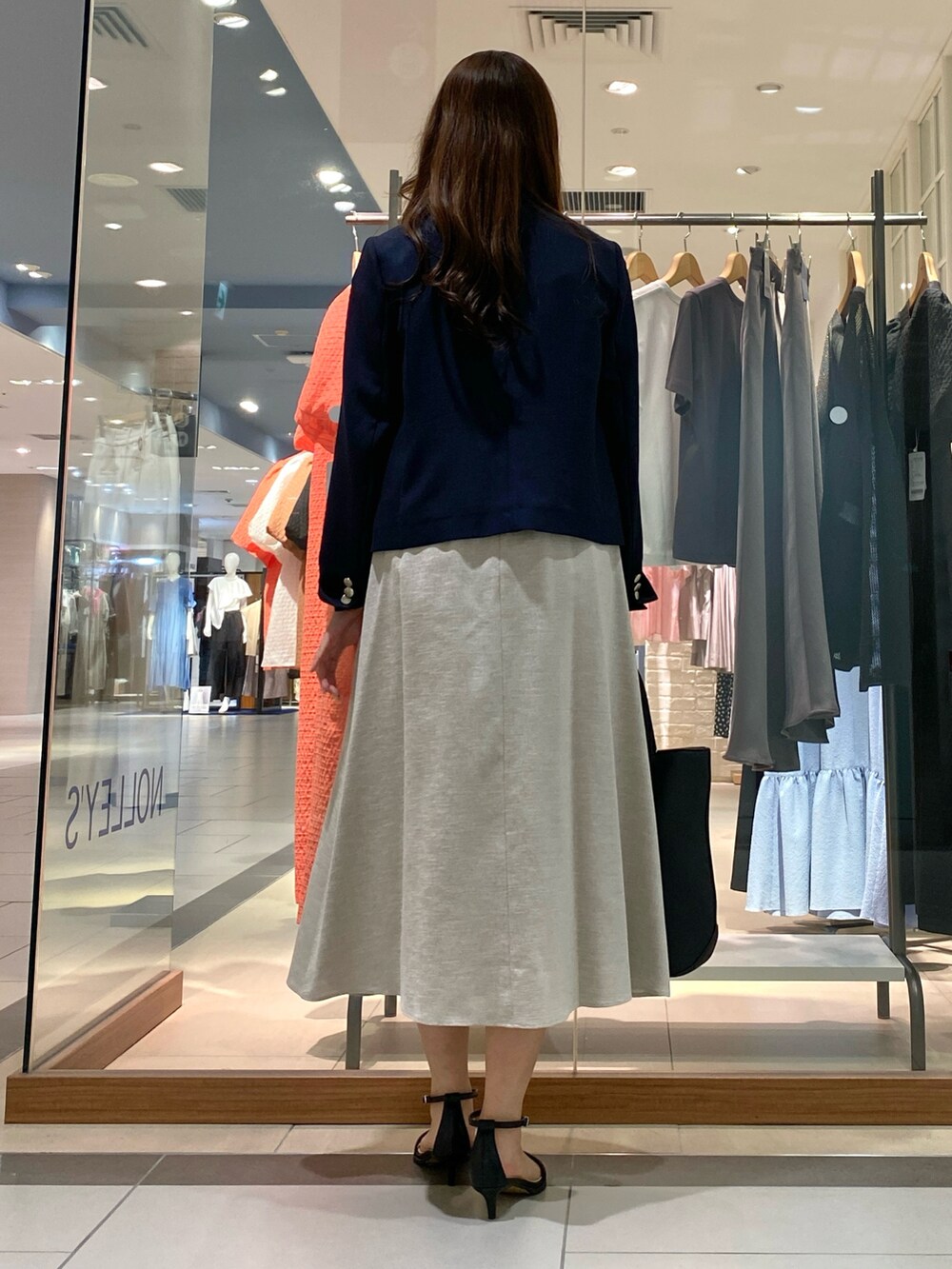 ブラック系のトートバッグ、ベージュ系のテーラードジャケット、オレンジ系のワンピースを着用したレディースの春コーディネートの5枚目の写真