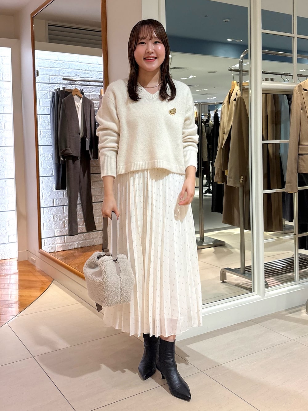 ホワイト系のスカート、ベージュ系のショルダーバッグ、ブルー系のニット/セーターを着用したレディースの冬コーディネートの8枚目の写真