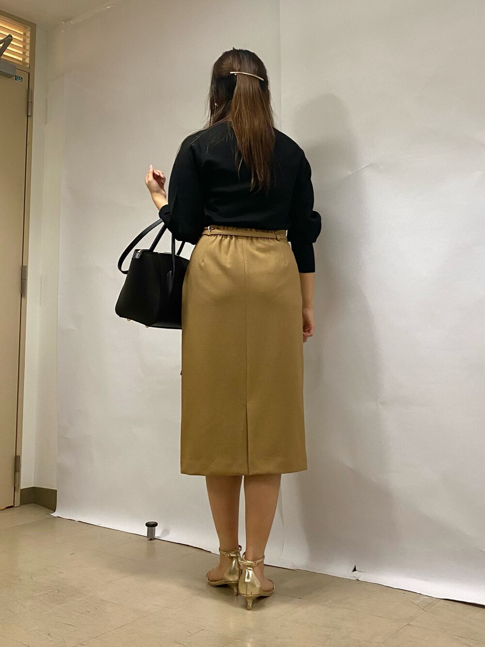 イエロー系のスカート、ブラック系のショルダーバッグ、ブラック系のニット/セーターを着用したレディースの秋コーディネートの3枚目の写真