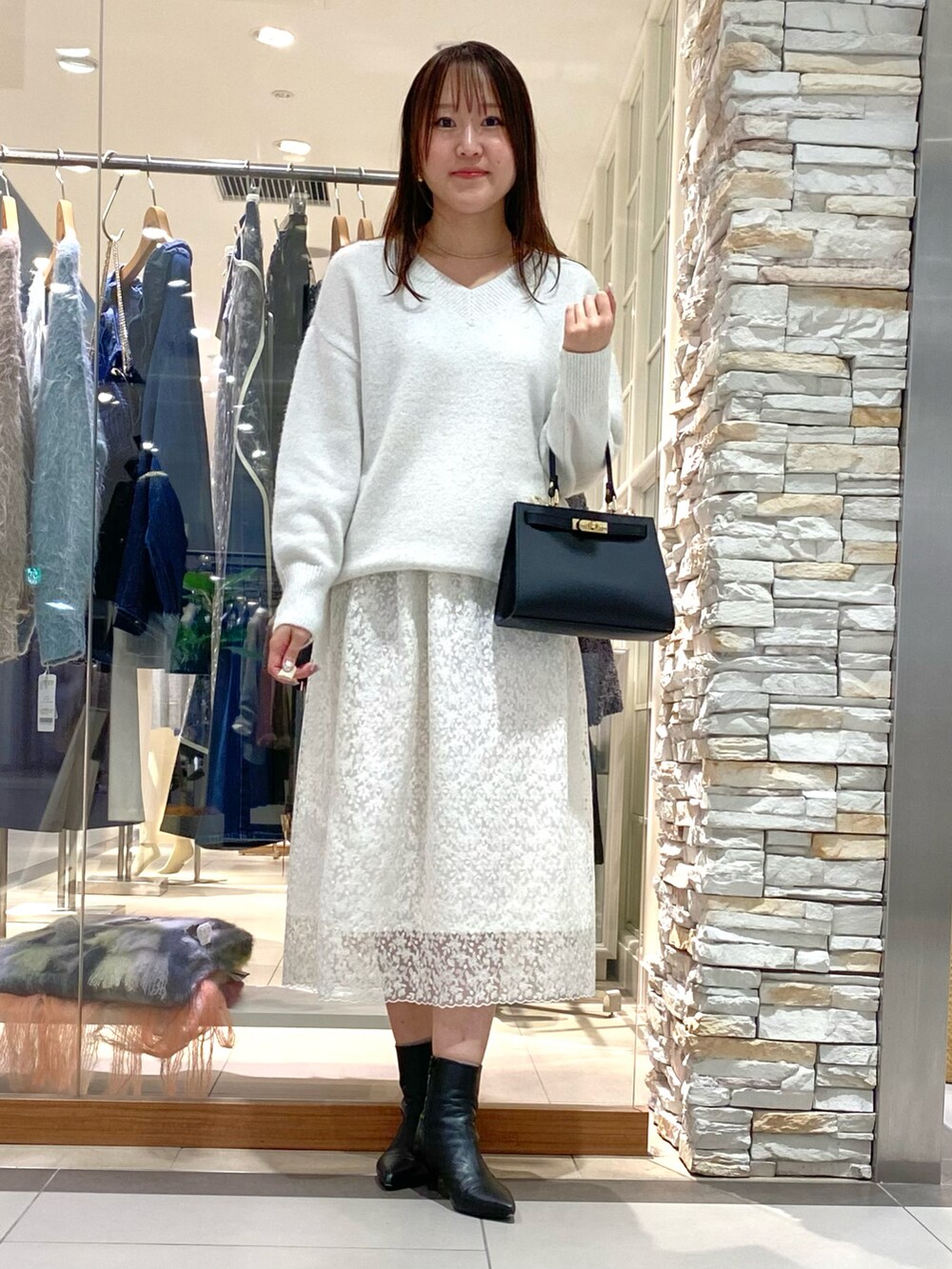 ブラック系のショルダーバッグ、ホワイト系のニット/セーター、ホワイト系のスカートを着用したレディースの冬コーディネートの5枚目の写真