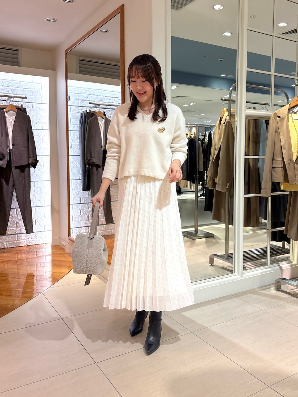 ホワイト系のスカート、ベージュ系のショルダーバッグ、ブルー系のニット/セーターを着用したレディースの冬コーディネートの3枚目の写真