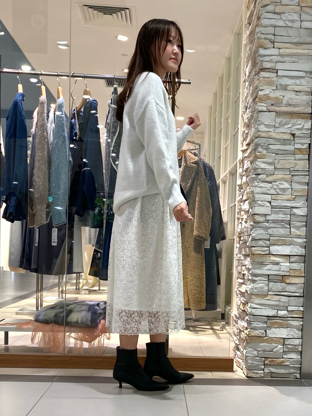 ブラック系のショルダーバッグ、ホワイト系のニット/セーター、ホワイト系のスカートを着用したレディースの冬コーディネートの2枚目の写真