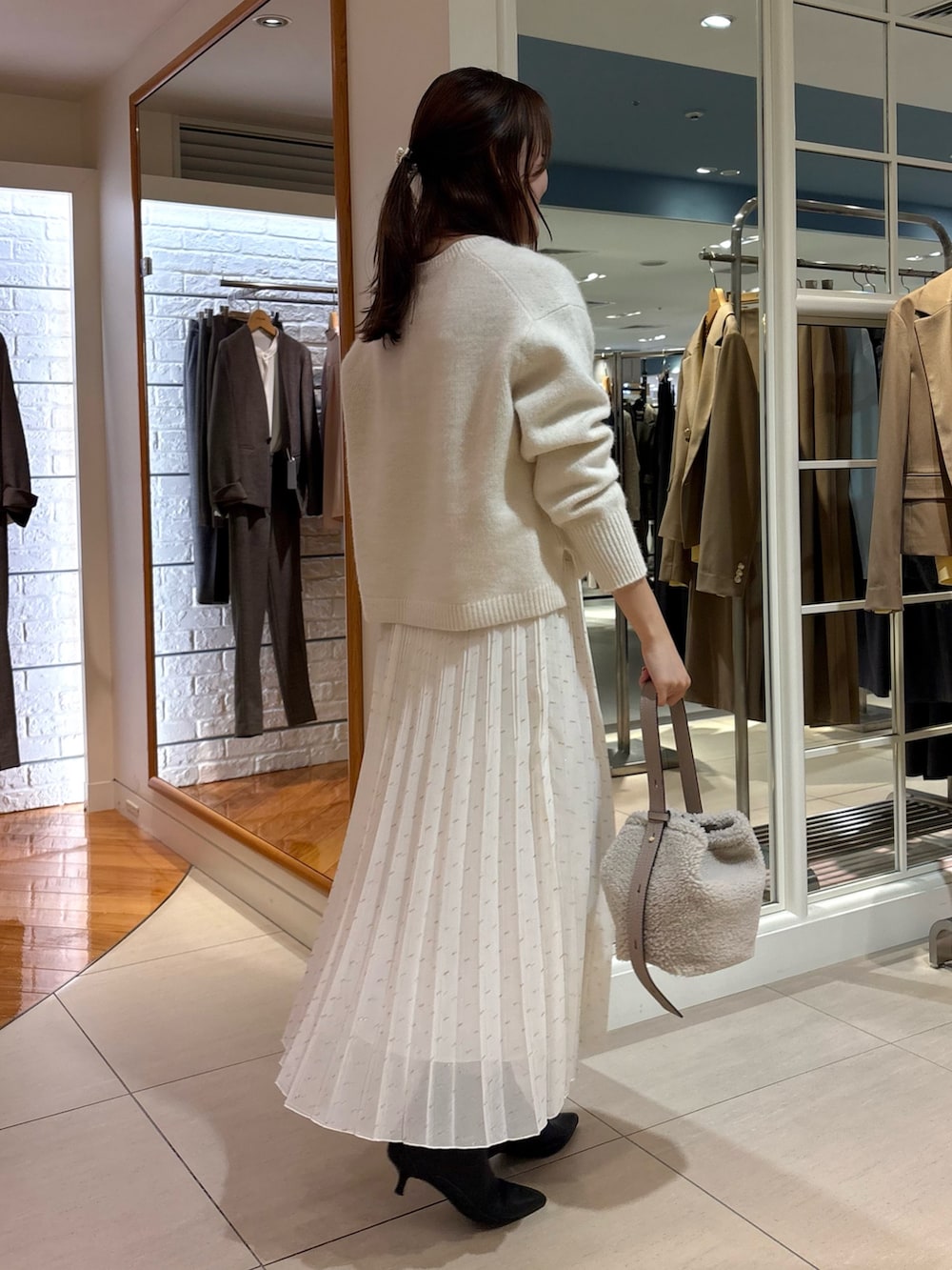 ホワイト系のスカート、ベージュ系のショルダーバッグ、ブルー系のニット/セーターを着用したレディースの冬コーディネートの6枚目の写真