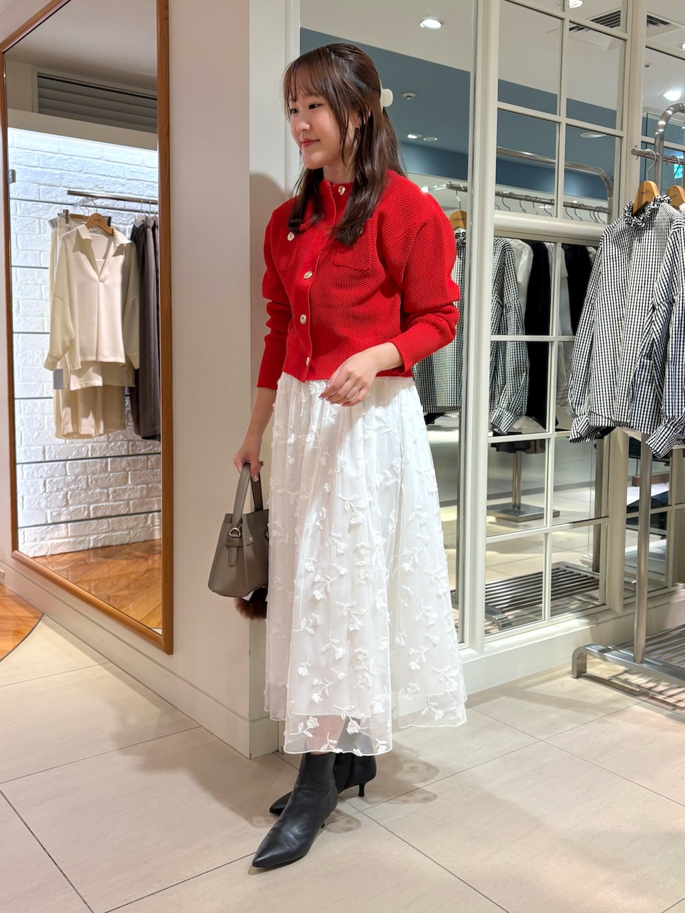 ホワイト系のスカート、レッド系のカーディガン/ボレロ、ベージュ系のショルダーバッグを着用したレディースの秋コーディネートの6枚目の写真