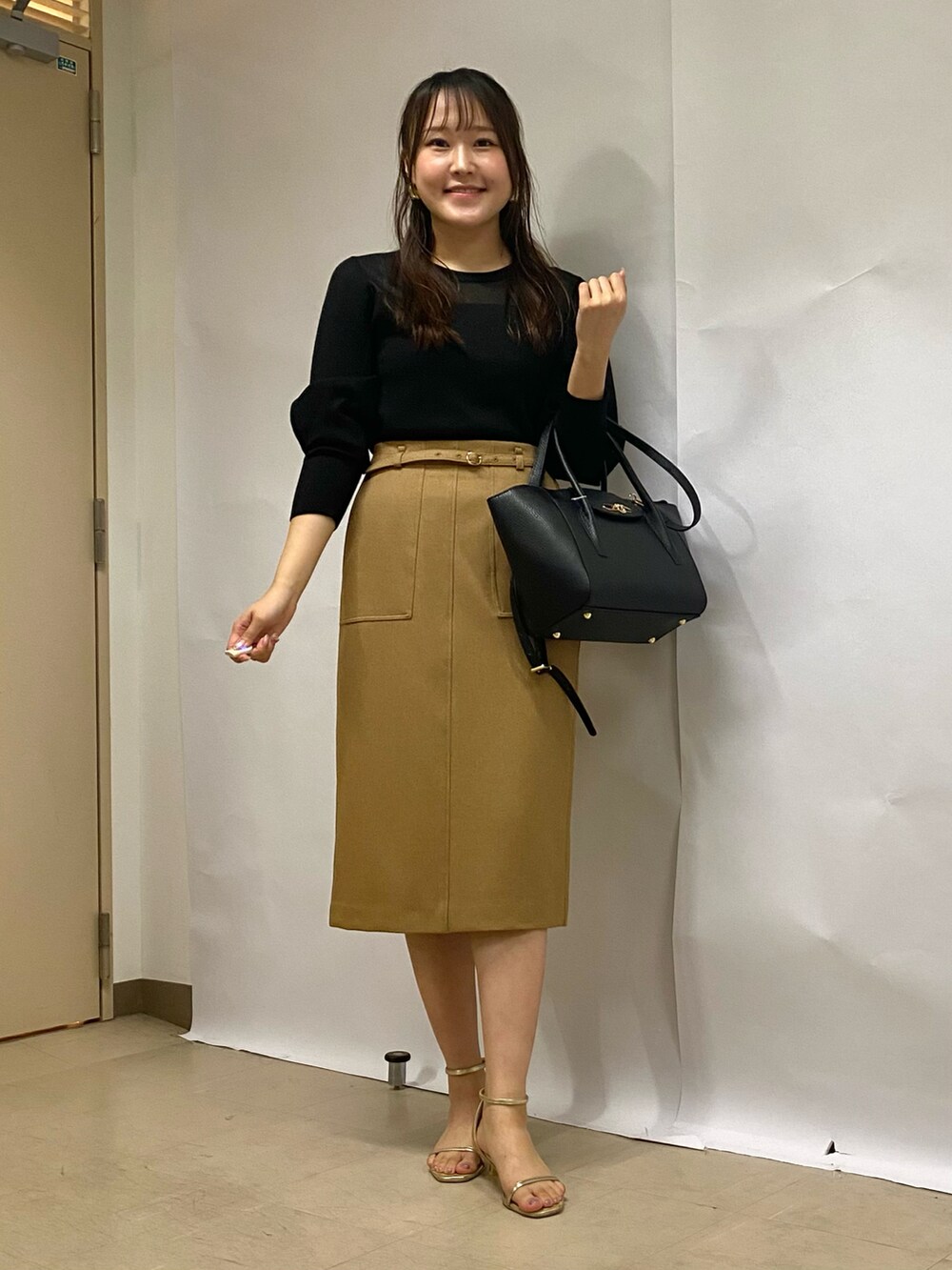 イエロー系のスカート、ブラック系のショルダーバッグ、ブラック系のニット/セーターを着用したレディースの秋コーディネートの5枚目の写真