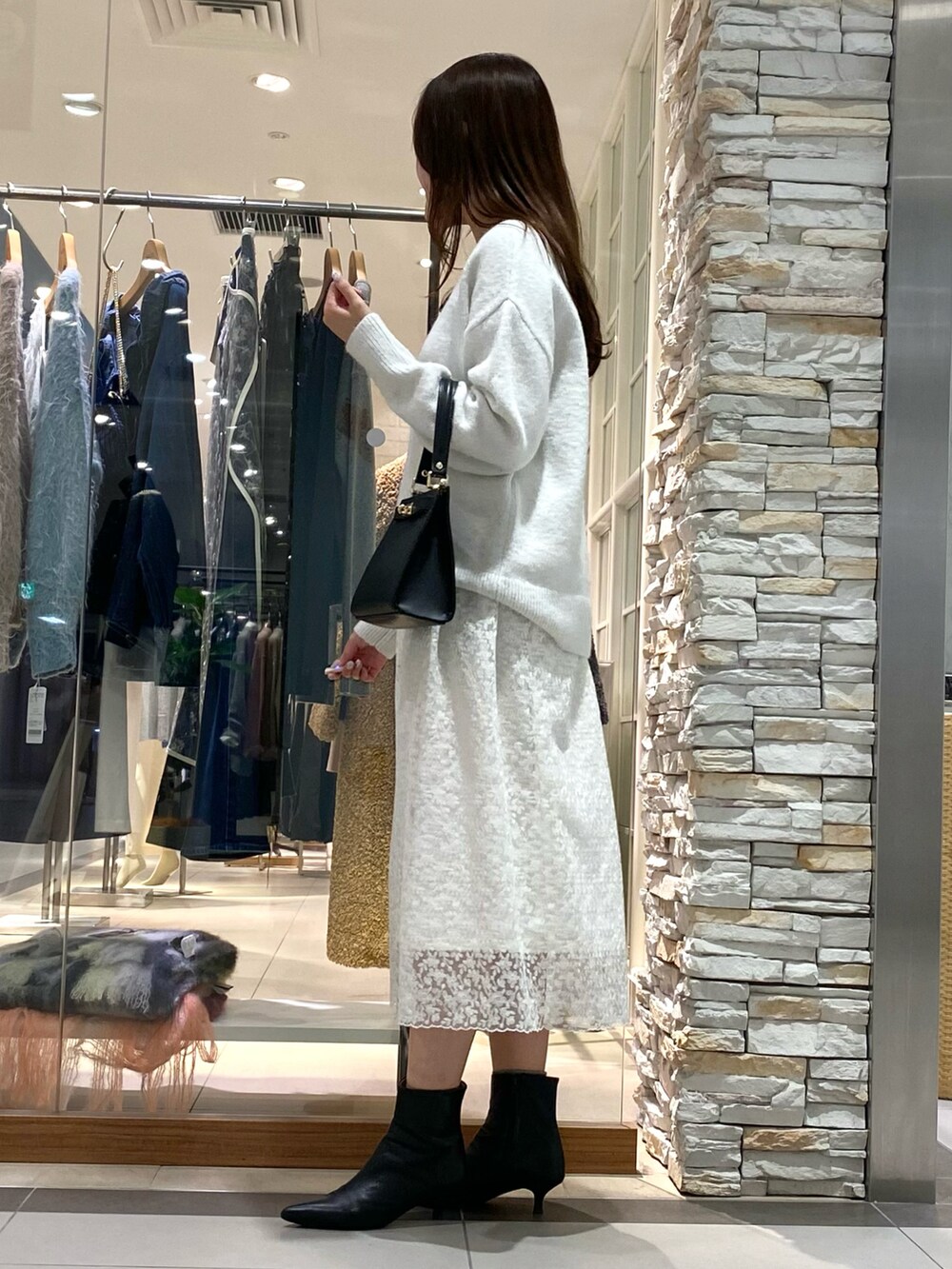 ブラック系のショルダーバッグ、ホワイト系のニット/セーター、ホワイト系のスカートを着用したレディースの冬コーディネートの4枚目の写真