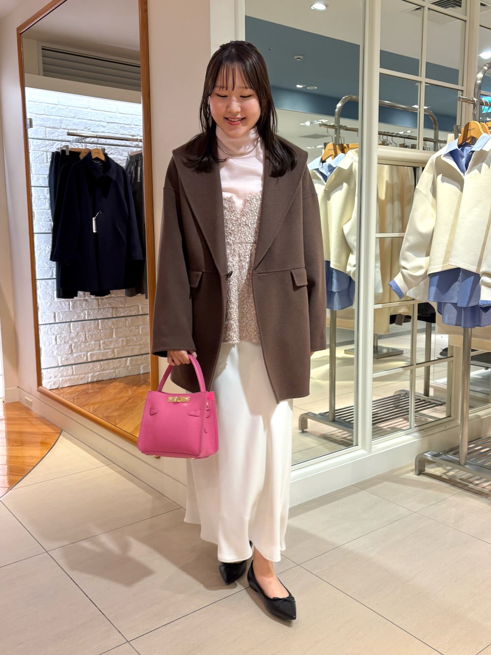 ベージュ系のキャミソール、ピンク系のニット/セーター、ホワイト系のスカートを着用したレディースの秋コーディネートの2枚目の写真