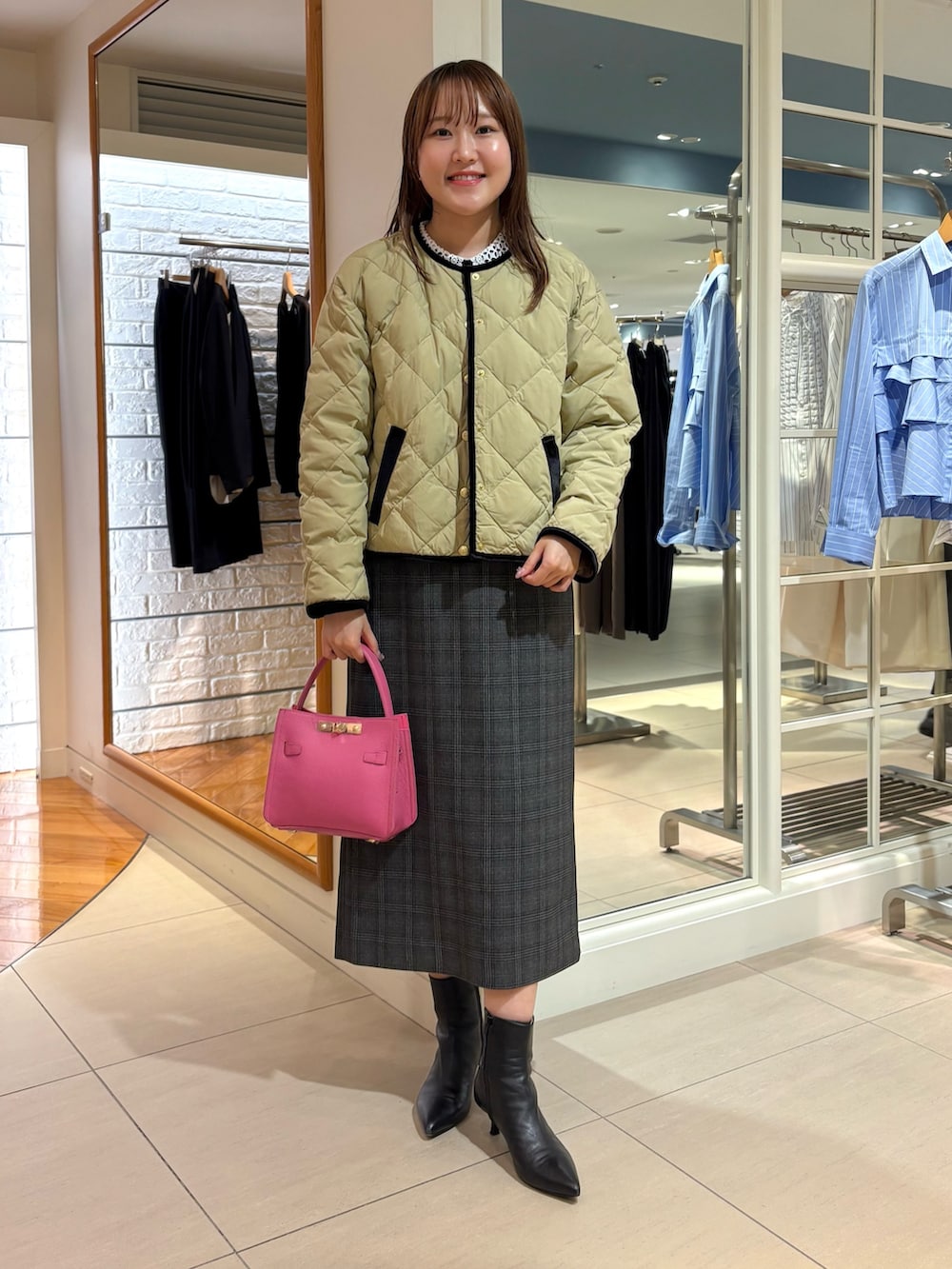 ベージュ系のショルダーバッグ、ベージュ系のダウンジャケット/コート、ブルー系のニット/セーターを着用したレディースの秋コーディネートの3枚目の写真