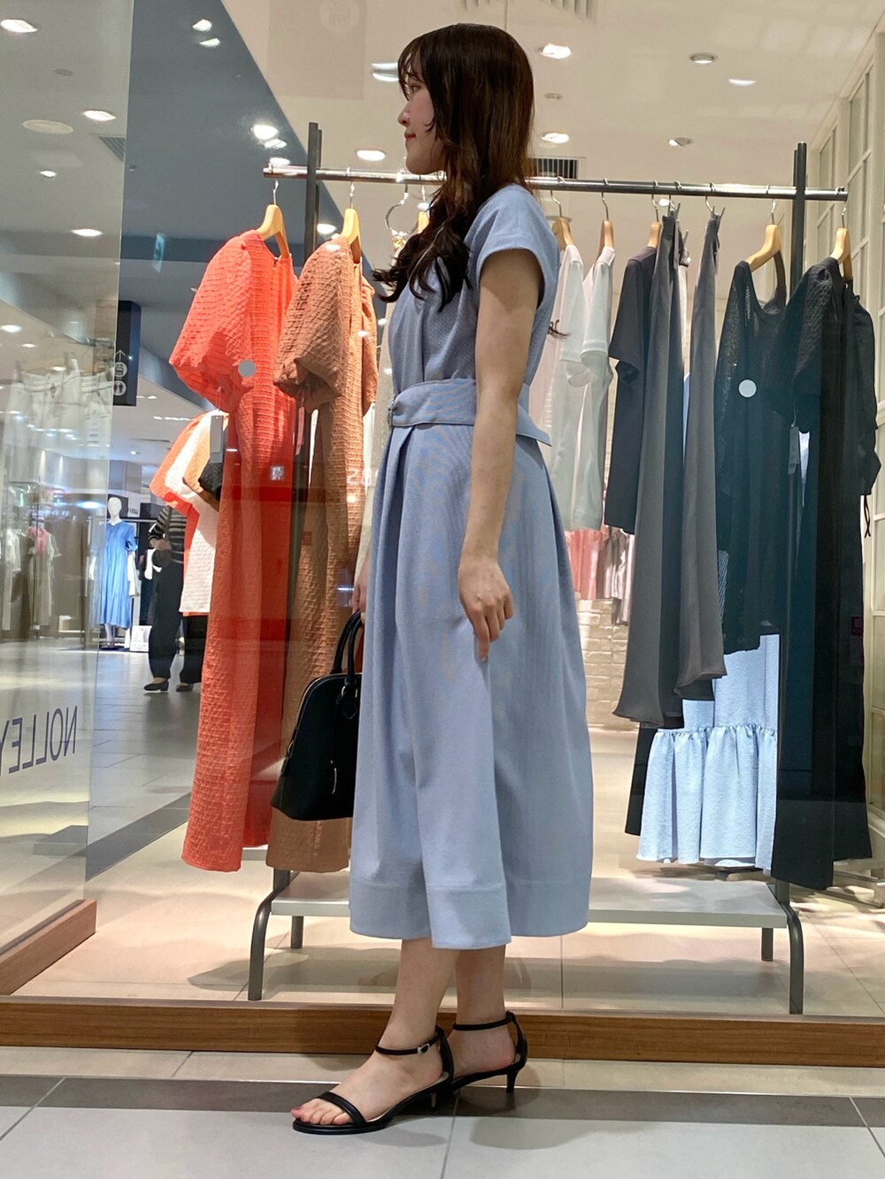 ブラック系のボストンバッグ、ブルー系のワンピース、シルバー系のサンダルを着用したレディースの春コーディネートの3枚目の写真