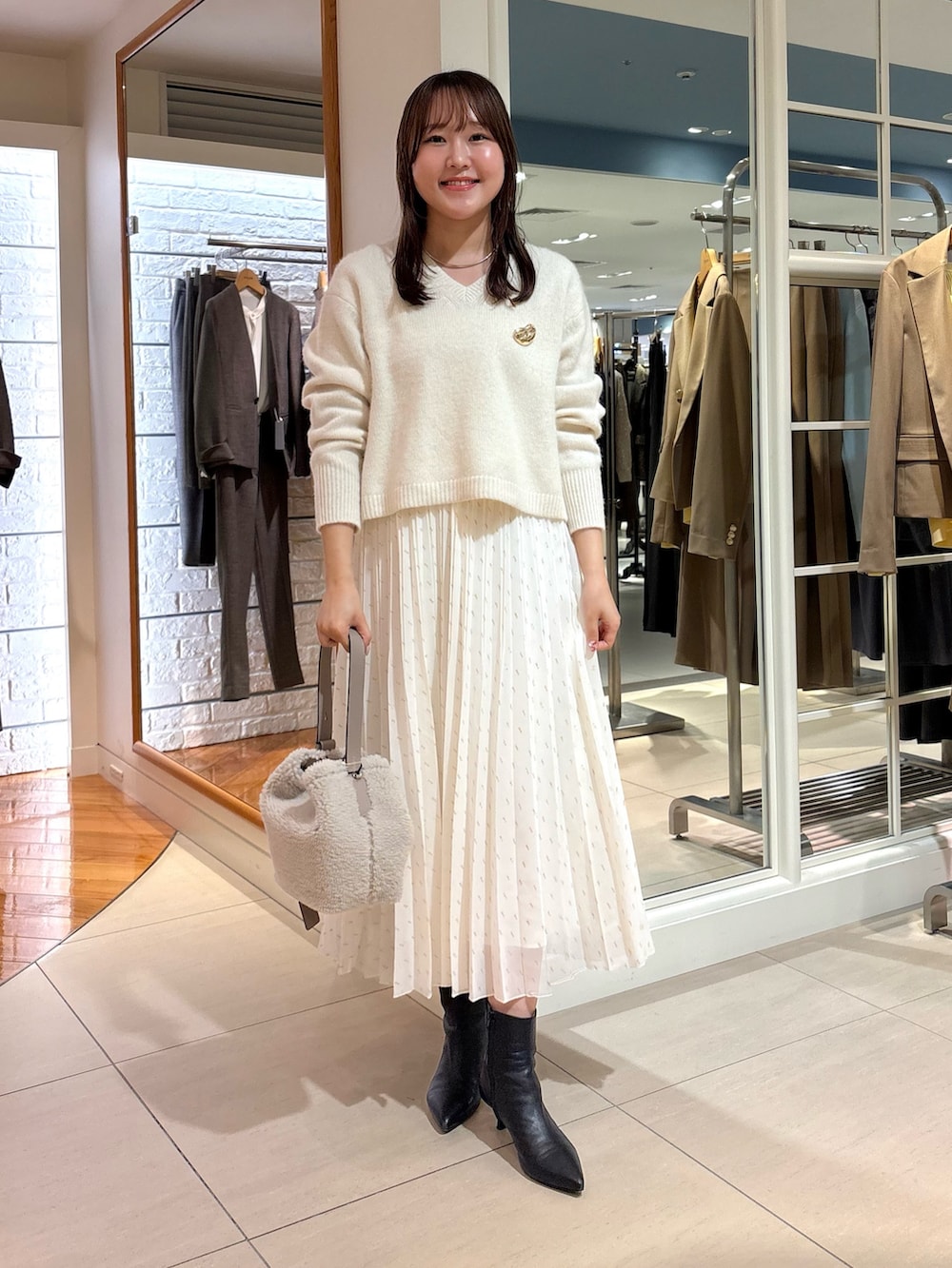 ホワイト系のスカート、ベージュ系のショルダーバッグ、ブルー系のニット/セーターを着用したレディースの冬コーディネートの9枚目の写真