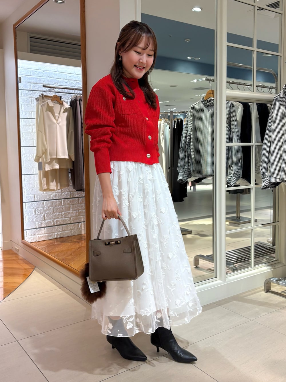 ホワイト系のスカート、レッド系のカーディガン/ボレロ、ベージュ系のショルダーバッグを着用したレディースの秋コーディネートの2枚目の写真