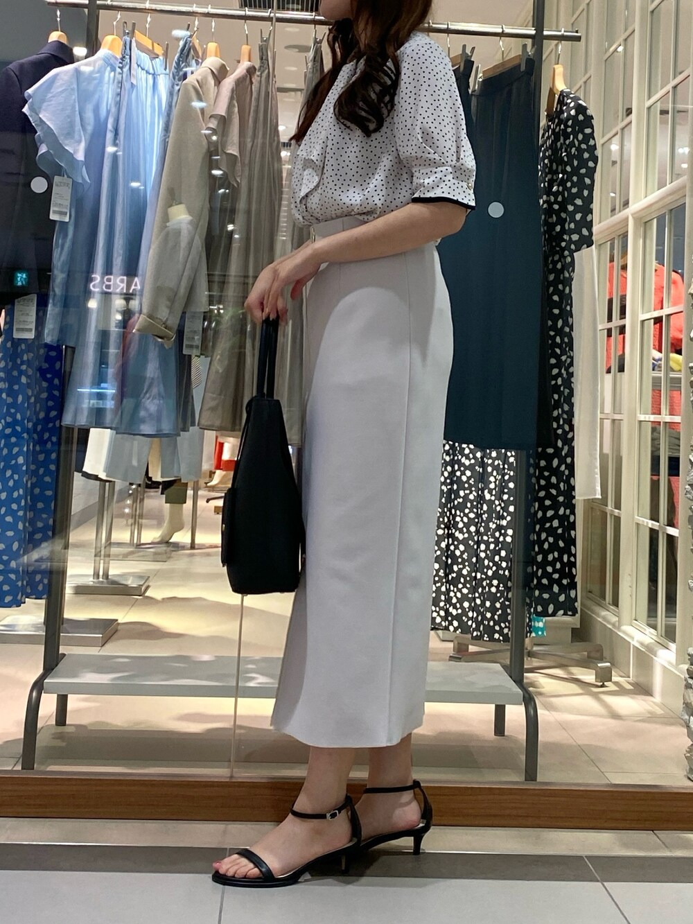 ホワイト系のシャツ/ブラウス、ホワイト系のスカート、ブラック系のトートバッグを着用したレディースの夏コーディネートの2枚目の写真