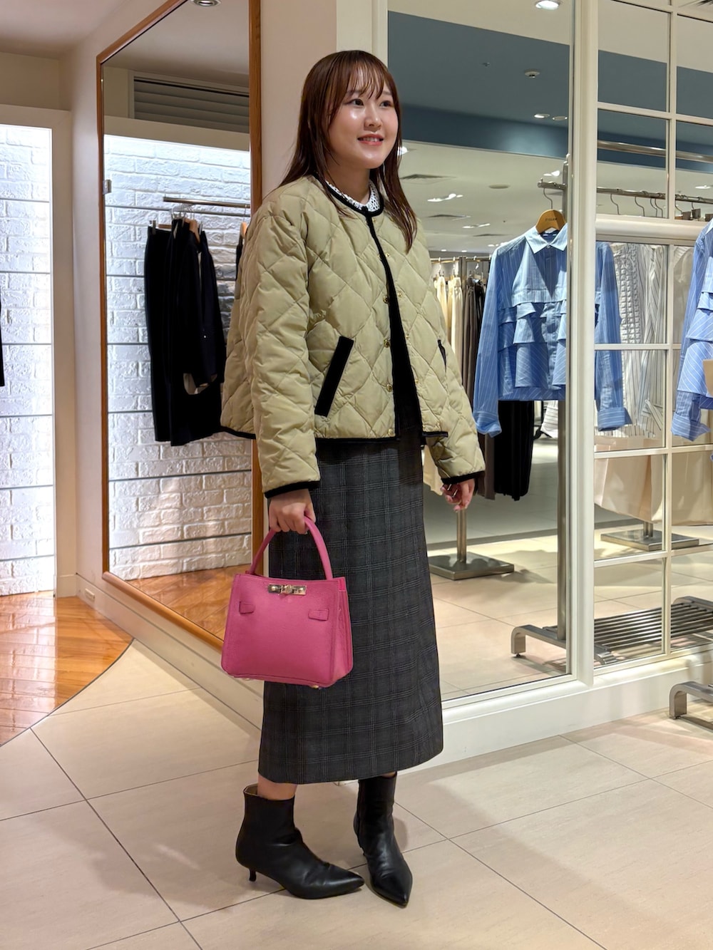 ベージュ系のショルダーバッグ、ベージュ系のダウンジャケット/コート、ブルー系のニット/セーターを着用したレディースの秋コーディネートの2枚目の写真