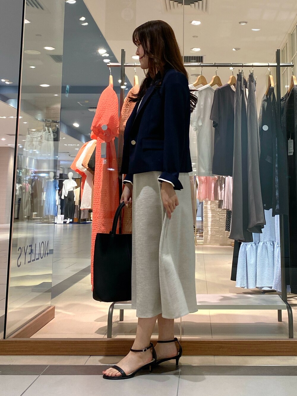 ブラック系のトートバッグ、ベージュ系のテーラードジャケット、オレンジ系のワンピースを着用したレディースの春コーディネートの3枚目の写真