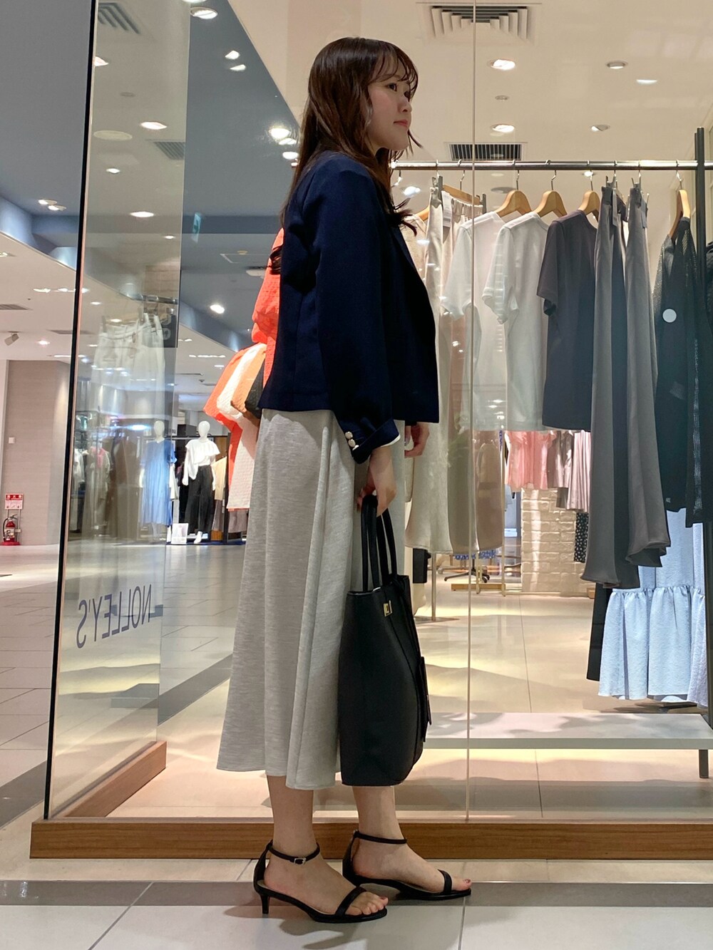 ブラック系のトートバッグ、ベージュ系のテーラードジャケット、オレンジ系のワンピースを着用したレディースの春コーディネートの4枚目の写真