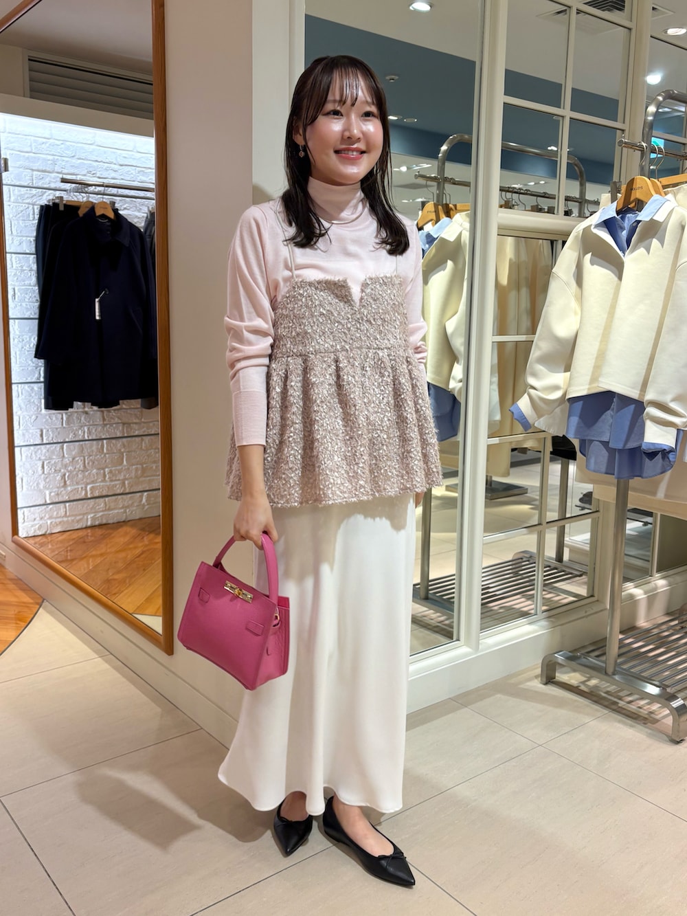 ブラック系のショルダーバッグ、ベージュ系のキャミソール、ピンク系のニット/セーターを着用したレディースの秋コーディネートの2枚目の写真