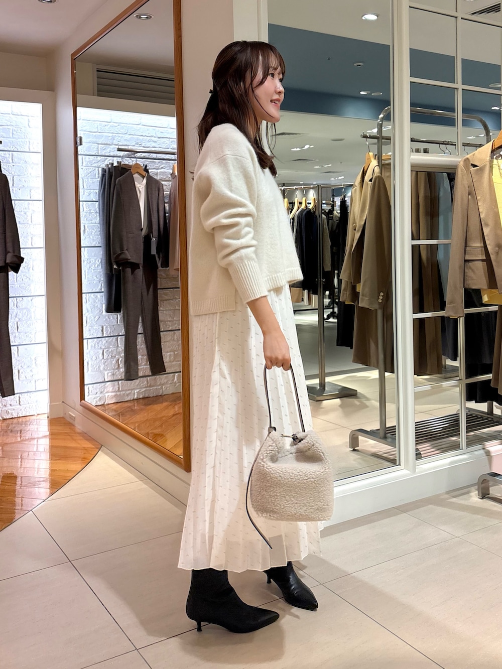 ホワイト系のスカート、ベージュ系のショルダーバッグ、ブルー系のニット/セーターを着用したレディースの冬コーディネートの7枚目の写真